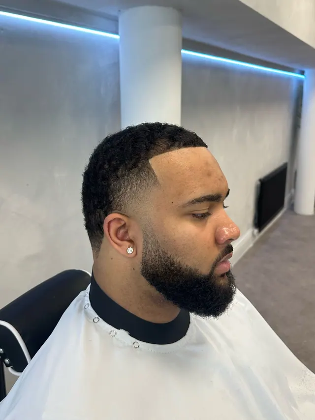 A skin fade with a line-up and a beard